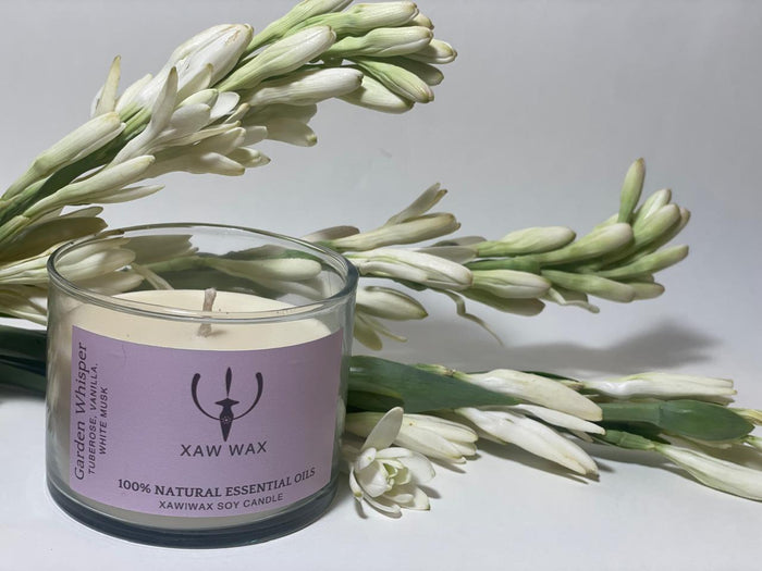 Garden Whisper soy candle surrounded by fresh tuberose flowers