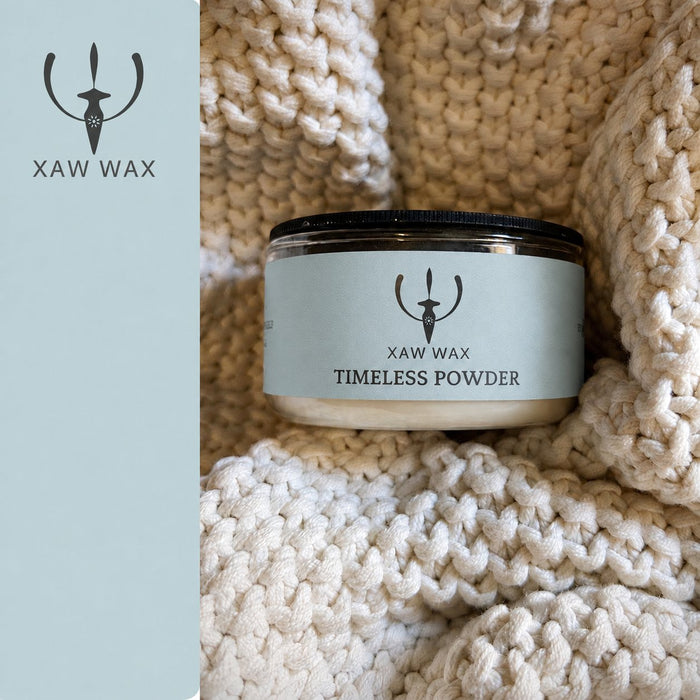 Timeless Powder 100 g candle in a cream blanket with a coordinated blue-gray label and full XAW strip